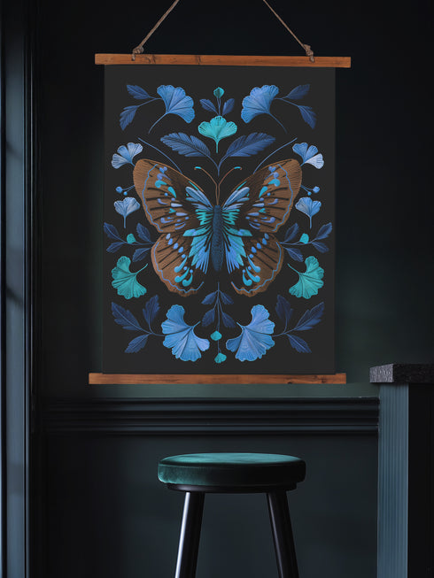Wall hanging tapestry featuring a large copper butterfly with turquoise and azure blue markings surrounded by blue ginkgo leaves on black background. The textile hangs from wooden dowels with twine, showing detailed 3D embroidery-like texture.
